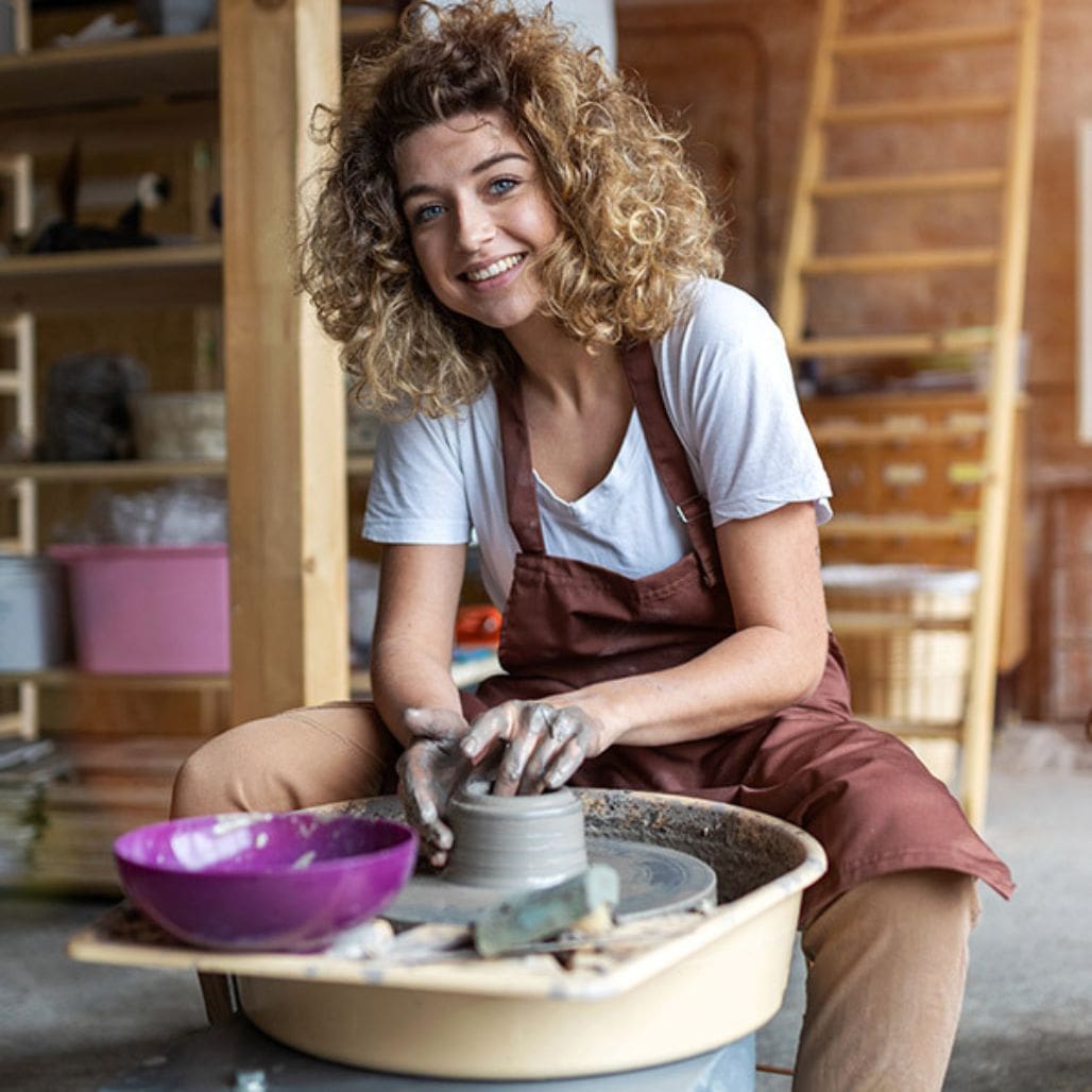 Lady smiling whilst sculpting on a Gladstone G34 Bailey Wheel